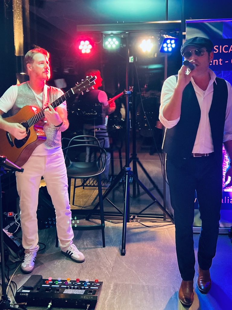 Musiker spielt Gitarre, Sänger mit Sonnenbrille und Kappe singt dazu